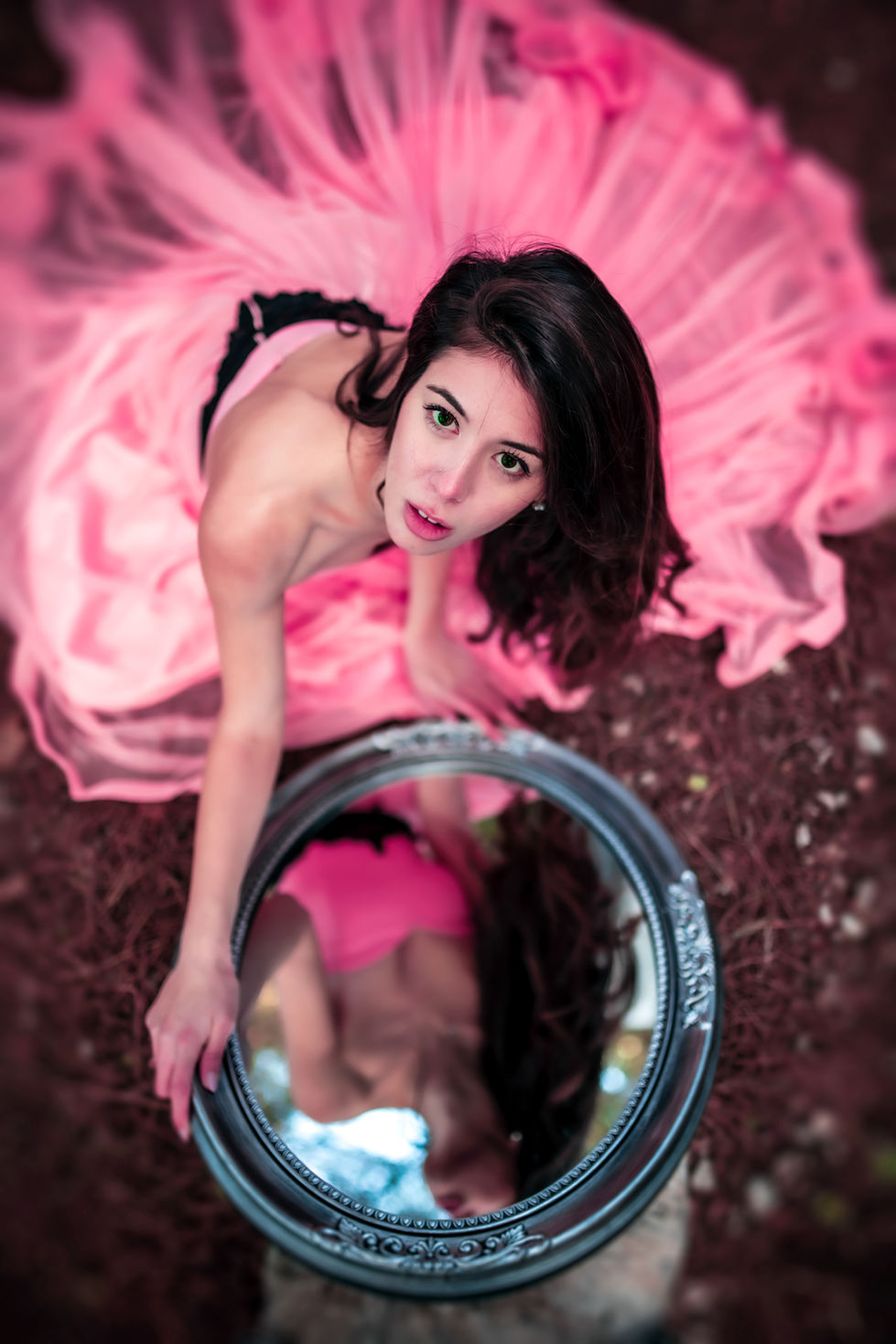 a woman in a pink dress looks at her reflection in a mirror