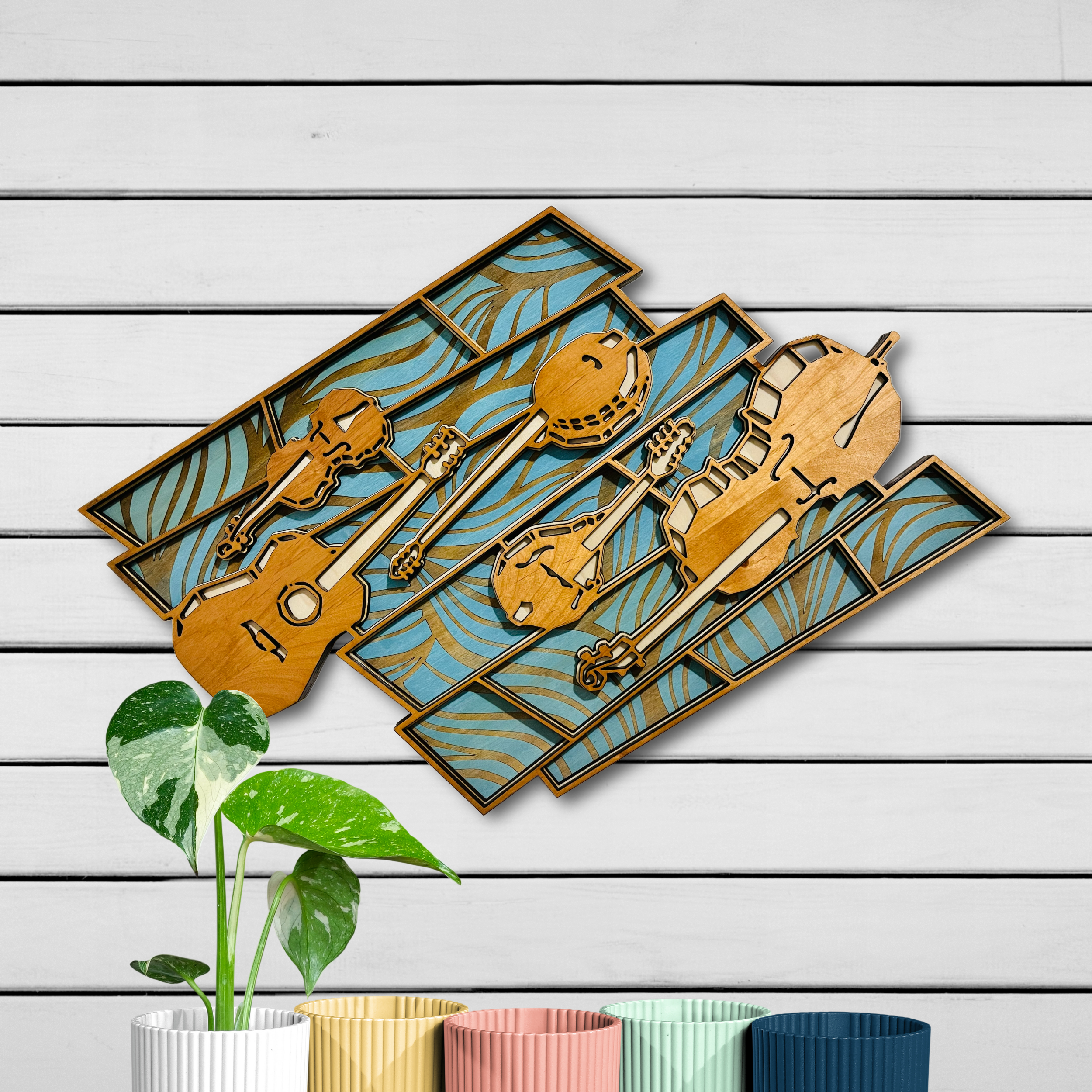 Laser cut wood wall art depicting five folk instruments above an intricate wavy background.