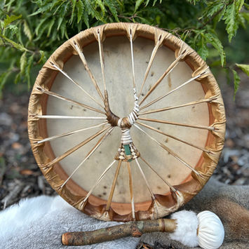 rear view of a deer hide shamanic drum resting against a tree