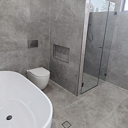 Post construction cleaning Sydney - newly built bathroom with grey tiles, glass shower and modern fixtures cleaned to handover standard by Flawless Sydney Cleaning
