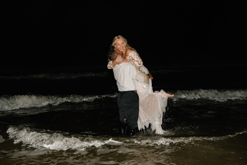 bride and groom jump into the ocean after their wedding at the Delamater House