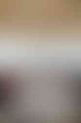 Round table with white tablecloth, white chairs, and a floral centerpiece on a covered outdoor deck overlooking water and a distant city skyline.