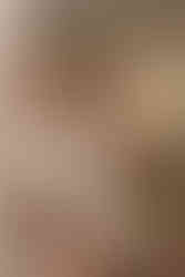 A group of women in dresses pose for a photo while looking into a large mirror in a room.