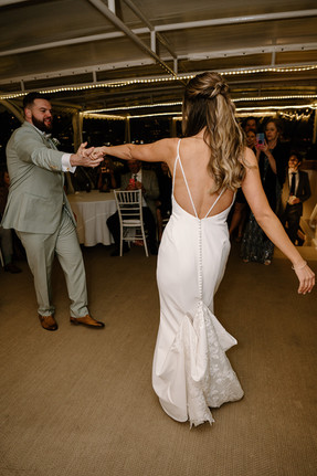 A bride and groom dance closely at a wedding reception, surrounded by seated guests at their boston boat wedding