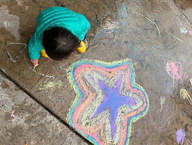 Meghan and her youngest daughter drawing with chalk on wet concrete. Her daughter experimenting next to Meghan's drawing of a star.