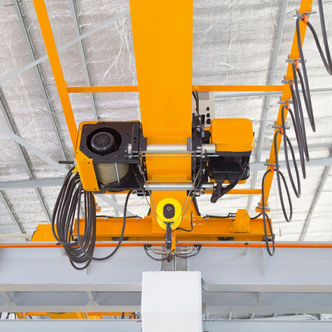 Overhead crane and hook inside factory building for lifting work.