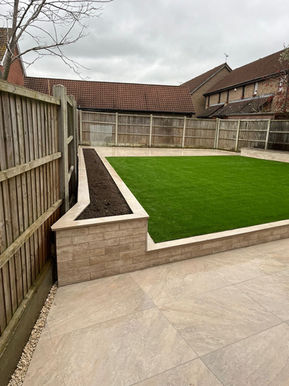 Split face tile wall in garden makeover Rayleigh Essex with patio and artificial grass