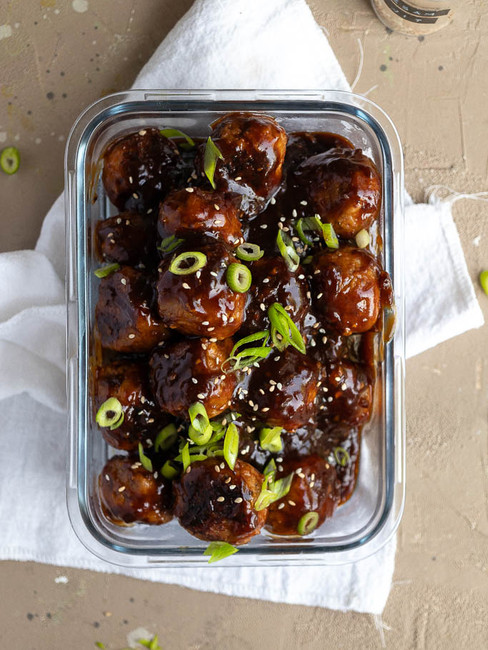 Indische kipgehaktballetjes in ketjapsaus, gegarneerd met bosui en sesamzaadjes