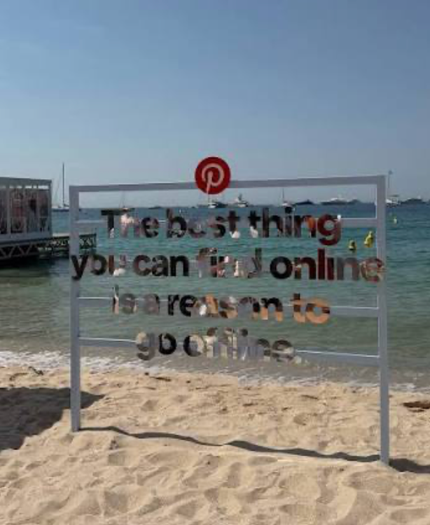 A sign on a beach in silver foil letters with the words the best thing you can find online is a reason to go offline