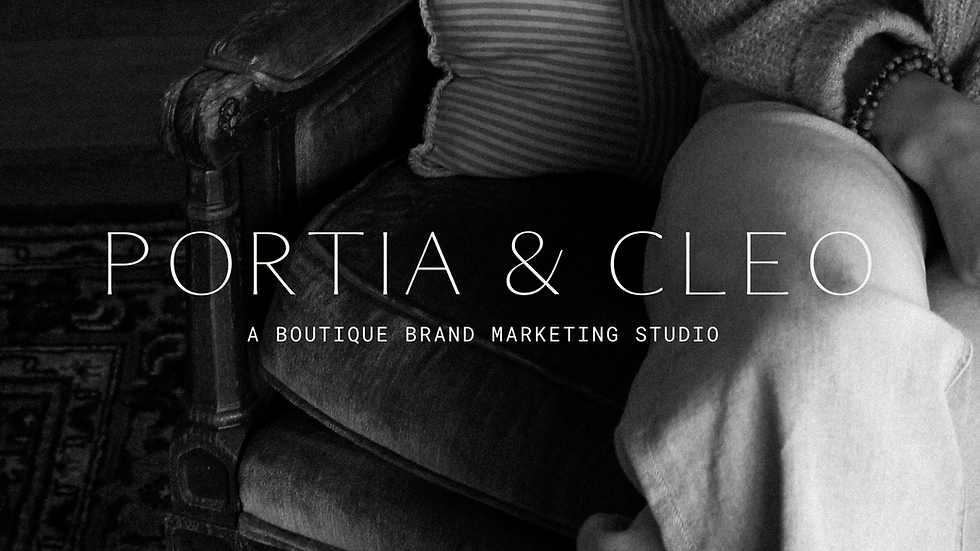 Black-and-white image of a person sitting in a cushioned armchair, hands resting on their lap, wearing a textured sweater and pants. Overlaid text reads: “PORTIA & CLEO” with the subtitle “A Boutique Brand Marketing Studio.”