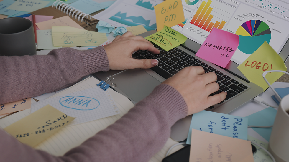 Hands typing on a laptop, surrounded by colorful sticky notes and charts. Notes include times, numbers, and names, creating a busy scene.