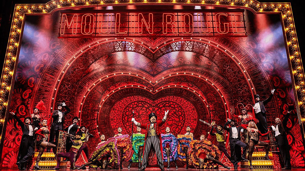 Moulin Rouge! The Musical - Performers in colorful costumes dance under a vibrant red, heart-shaped stage with "Moulin Rouge" in lights, creating a lively mood.