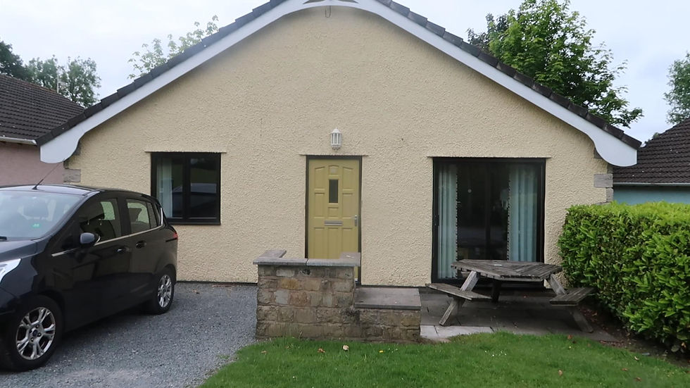 Exterior view of the Diamond Cottage at Ribby Hall Village with private parking, picnic bench seating area, and front lawn.