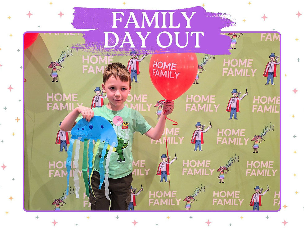 Boy holding a red balloon and blue jellyfish craft at Family Day Out, standing before a Home Family backdrop.