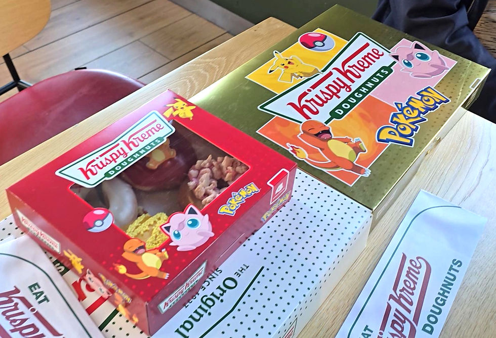 Two Krispy Kreme Pokémon doughnut boxes on a wooden table, with Pikachu, Jigglypuff, Charmander, and Poké Ball logos.