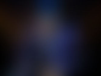 The Old Vic’s production of A Christmas Carol - Performers in dark coats and top hats dance energetically on a stage lit by hanging lanterns and blue spotlights, conveying joy and elegance.