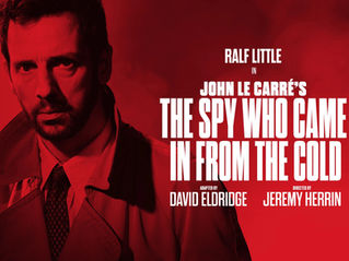 Red poster of serious man in trench coat for John le Carré’s The Spy Who Came In From the Cold, starring Ralf Little.