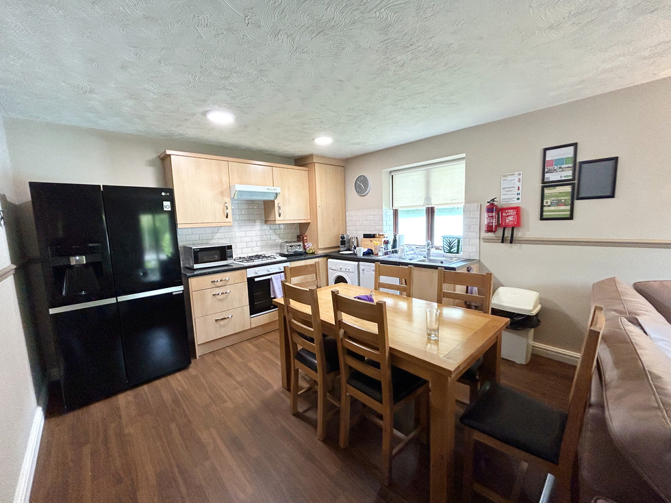 Open-plan kitchen and dining area in the Diamond Cottage with dining table, American-style fridge freezer, oven, microwave, and family seating area.