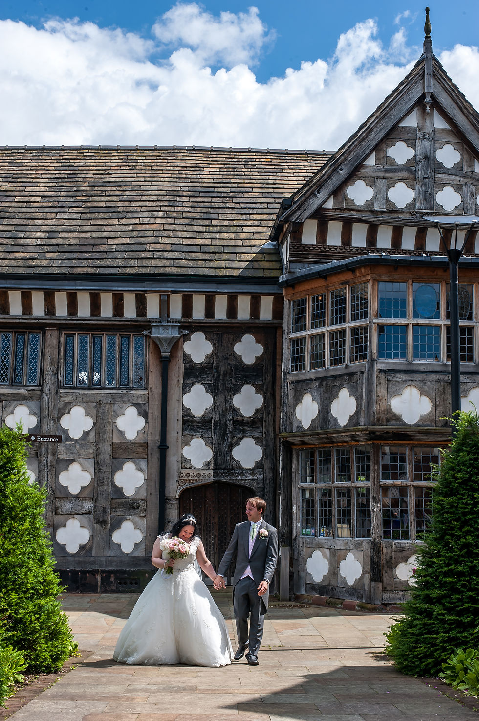 Sarah and Lawrence walking hand in hand in the gardens at Ordsall Hall after their wedding ceremony.