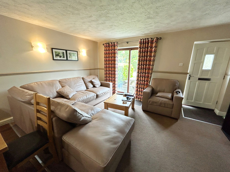 Spacious open-plan lounge area inside the Diamond Cottage at Ribby Hall Village featuring large leather sofas, patio doors, and cosy neutral décor.