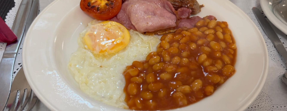 Full English breakfast served at Mabledon Court Hotel London with fried egg, bacon, sausage, baked beans and grilled tomato.