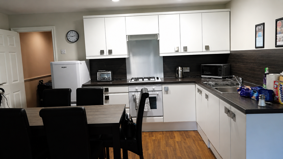 Modern self-catering kitchen and dining area with white cupboards, dining table, microwave, toaster and integrated oven