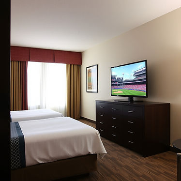 hotel room with two beds and large tv on dresser in front.jpg
