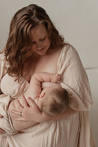 Mother looking down at nursing infant, wearning a gauze dress