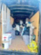 Back of a van loaded with goods, cooker, suitcase, yoghurt, containers, boxes, BinBags, straps