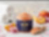 Jar of Grams Peach Body Scrub with peaches and wooden scoop
