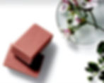 Two brown soaps with a petri dish of flowers on a white surface.