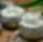White cream in small containers, scattered lavender on wooden surface.