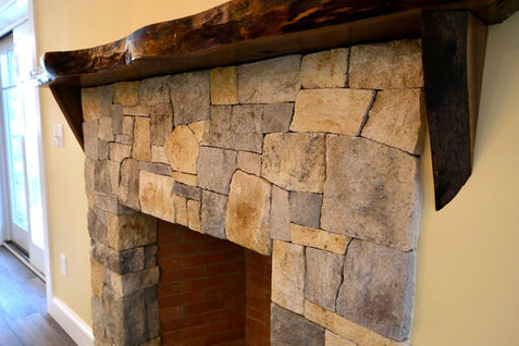 Hand laid stone fireplace in lower level recreation room of new home under construction.