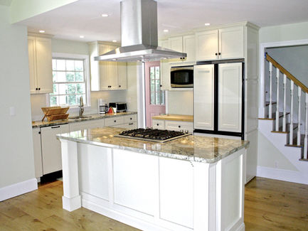 A handsome granite center island is the focal point of the kitchen redesign by Ogunquit Home Design Showroom in Maine.