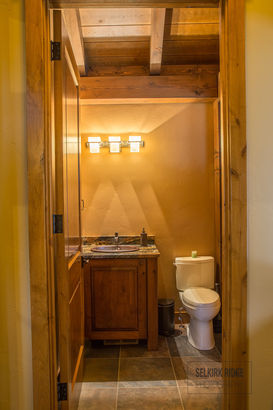 Cozy rustic bathroom with wooden vanity, sink, toilet, and tiled floor.