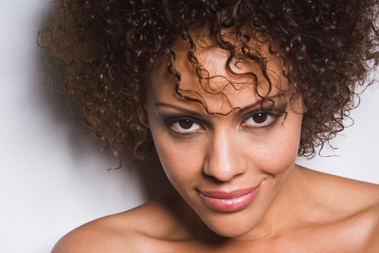 Graceful light brown-skinned woman with captivating eyes, showcasing the positive outcomes of an under-eye treatment, which has contributed to a refreshed and radiant appearance.