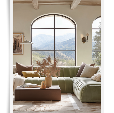 living room space with a large green feature sectional sofa with decorative pillows and a coffee table in front and a large window with a view of the mountains behind the sofa
