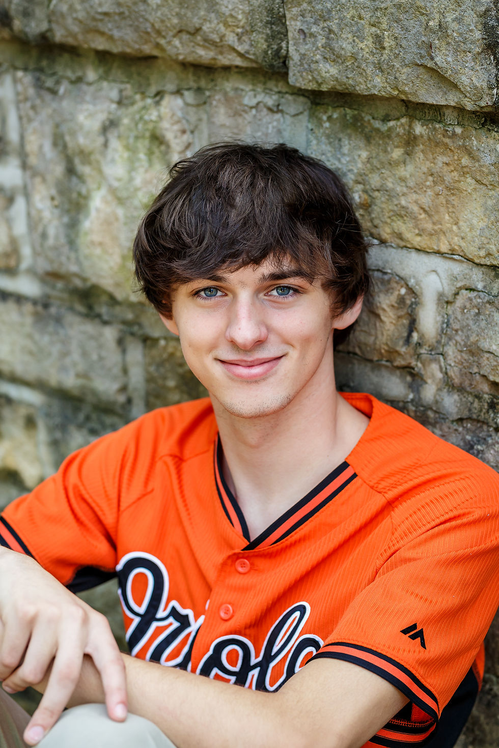 Westerville North senior portrait wearing orange jersey against stone wall