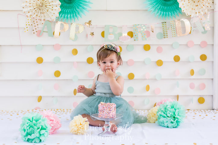 Baby girl in teal dress eats smash cake for photoshoot near Westerville with cute backdrop