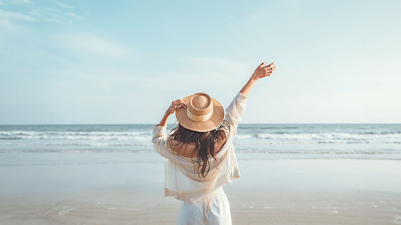 Summer beach vacation concept, Happy young woman with hat relaxing with her arms raised to