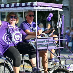 A couple waves in k-state gear while riding a 4-wheeled bike.
