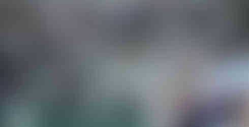 K-State baseball players lean out from the dugout while watching the game.