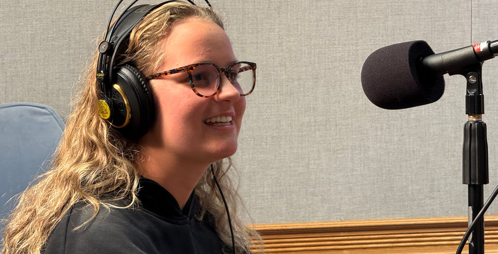 Anne Borberg smiles while sitting in front of a microphone in the studio at Wildcat 91.9.