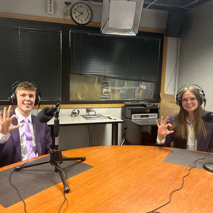 Lauren Wolters and Matthew Hendricks hold up the Powercat hand sign in Studio E of Wildcat 91.9.