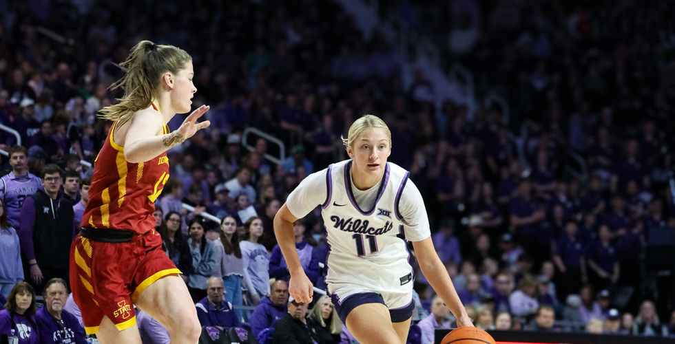 A K-State women's basketball player dribbles the ball towards the goal.