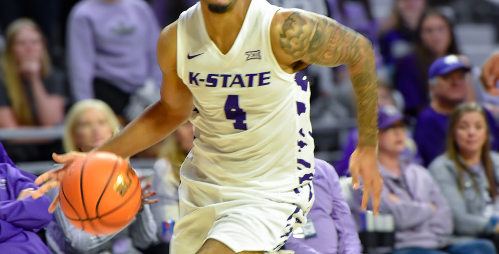 A K-State basketball player dribbles the ball down the court.