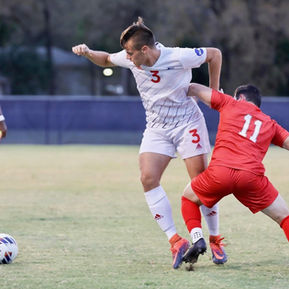 Nick Harlin (white)  challenges an opponent (red) for control of the ball during a soccer match.