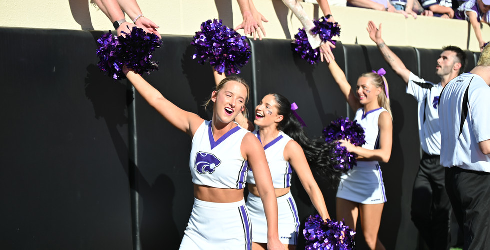 The K-State cheer team high fives fans in the crowd.