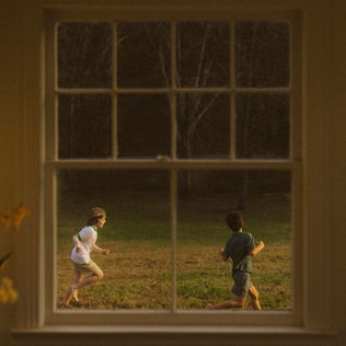 The album cover of "The Great Divide" Two children are joyfully running through a grassy field, captured through the panes of a window, with the warm glow of sunset highlighting their lively play.