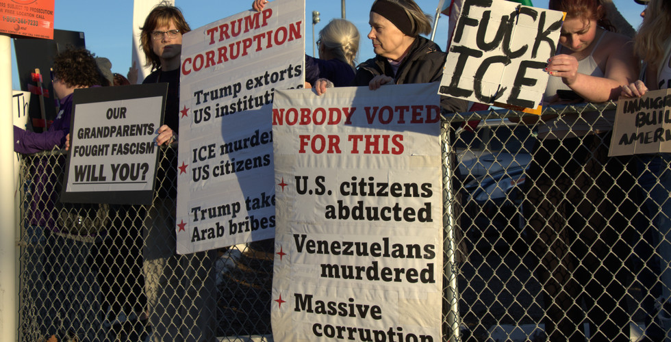 Protesters hold signs along a fence in Griffith Park.